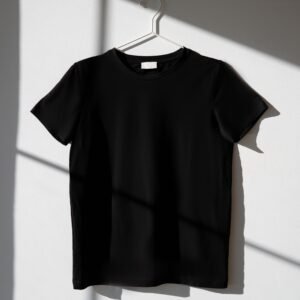 Black t-shirt hanging on a hanger against a white wall